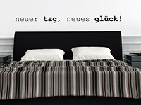 Spruch Wandtattoo Neuer Tag, neues Glück in schwarz über dem Bett